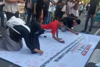 Foto: Sejumlah warga membubuhkan tanda tangan pada kain petisi yang digelar oleh KEPAK NTB di kawasan Car Free Day Taman Udayana, Mataram, Minggu (26/4/2026), sebagai bentuk dukungan terhadap pengusutan dugaan kasus gratifikasi DPRD NTB dan desakan pemanggilan Gubernur NTB sebagai saksi kunci.(JD09)