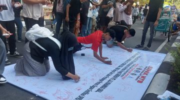 Foto: Sejumlah warga membubuhkan tanda tangan pada kain petisi yang digelar oleh KEPAK NTB di kawasan Car Free Day Taman Udayana, Mataram, Minggu (26/4/2026), sebagai bentuk dukungan terhadap pengusutan dugaan kasus gratifikasi DPRD NTB dan desakan pemanggilan Gubernur NTB sebagai saksi kunci.(JD09)