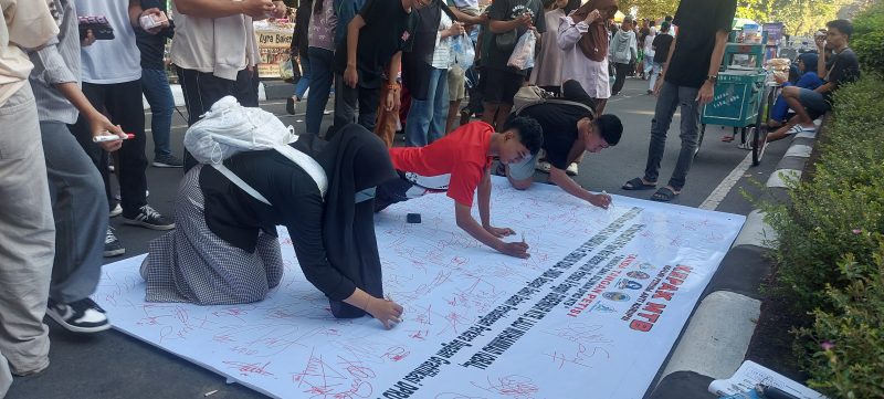 Foto: Sejumlah warga membubuhkan tanda tangan pada kain petisi yang digelar oleh KEPAK NTB di kawasan Car Free Day Taman Udayana, Mataram, Minggu (26/4/2026), sebagai bentuk dukungan terhadap pengusutan dugaan kasus gratifikasi DPRD NTB dan desakan pemanggilan Gubernur NTB sebagai saksi kunci.(JD09)