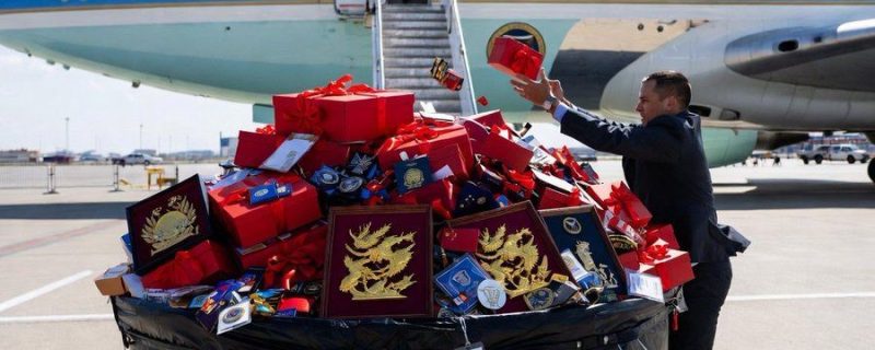 Foto: Seorang staf delegasi Amerika Serikat mengumpulkan dan memilah berbagai suvenir serta barang pemberian dari pejabat China di depan pesawat kepresidenan Air Force One, sebelum bertolak kembali ke Washington. Langkah sistematis ini dilakukan sebagai bagian dari prosedur keamanan siber guna mengantisipasi potensi risiko spionase digital terhadap objek sensitif. (Dok. Istimewa)